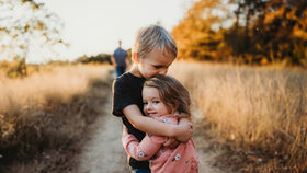 Zwei Kinder umarmen sich auf einem Feldweg