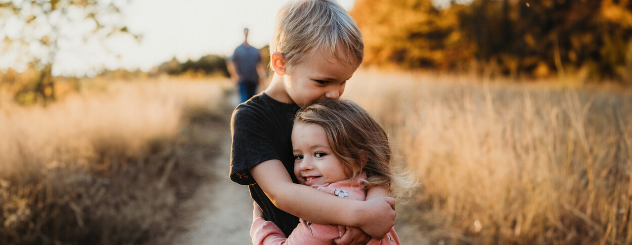 Zwei Kinder umarmen sich auf einem Feldweg